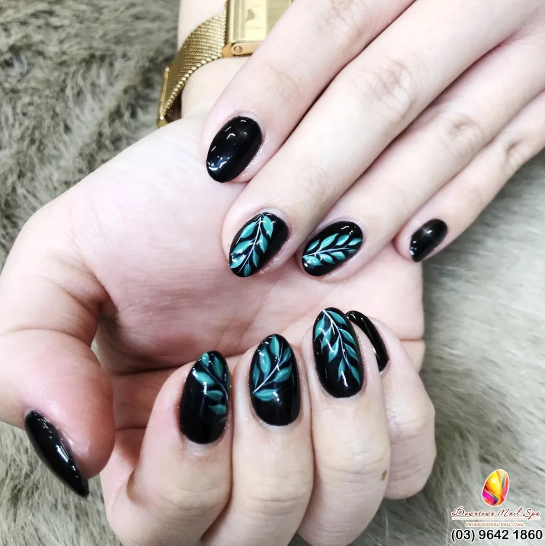 Black glossy nails with teal botanical leaf art and a gold watch &mdash; Downtown Nail Spa